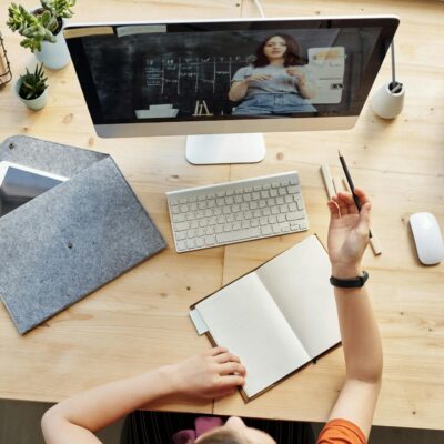 Teen girl actively learning in an organized home workspace via online class on a desktop computer.